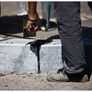 Hand and leg of a person smoothing concrete at a construction site.