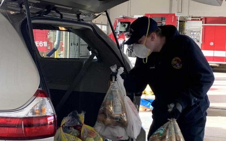 A Clinton Township firefighter loading produce into the back of a car.